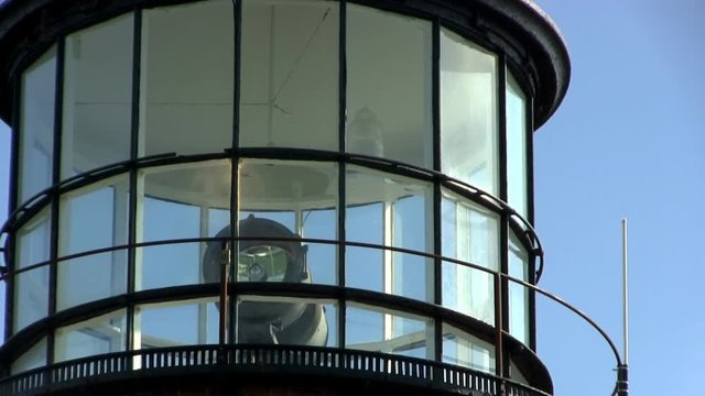 Close-up of lighthouse at Gay Head Aquinnah on Martha's Vineyard with rotating red and white lights behind glass against blue sky