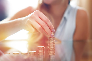 Woman building money column in sunset closeup