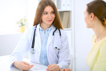 Doctor and  patient  have a talk while sitting at the desk near window