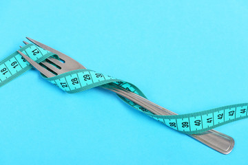 Fork of silver colour wrapped with cyan measuring tape