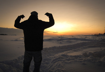Silhouette of a man standing in a snowy and winter landscape. Sunset and winter field. - 163011427