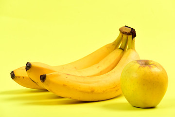 Bananas and juicy apple, isolated on yellow background