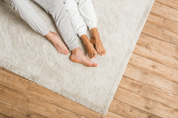 low section of young couple lying on carpet at home