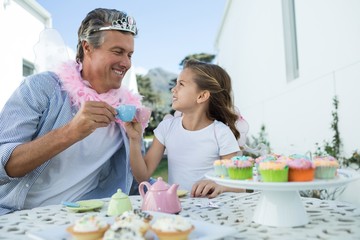 Smiling father and daughter in fairy costume toasting cup of tea - Powered by Adobe