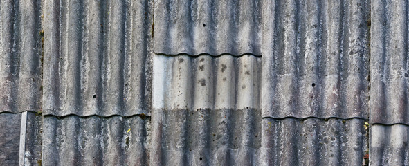 Naklejka premium Texture of an old vintage roof covered with wavy aged asbestos tiles.