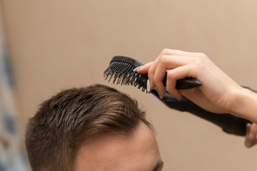 close up of female hairdresser drying her male customer's hair in her hairdressing salon