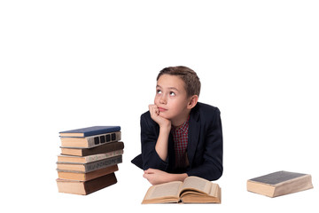 Cute boy in a suit lies and daydreaming on a white background. a pile of books.