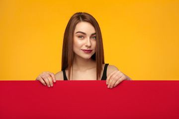 Stylish girl posing behind red cardboard