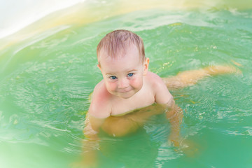 Fototapeta na wymiar Baby swims in a plastic pool in the nature