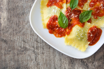 Ravioli with tomato sauce and basil on wooden table
