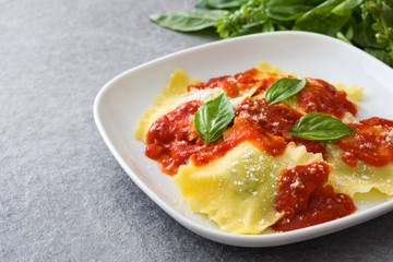Ravioli with tomato sauce and basil on gray stone
