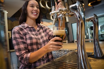 Beautiful barmaid preparing drink at bar