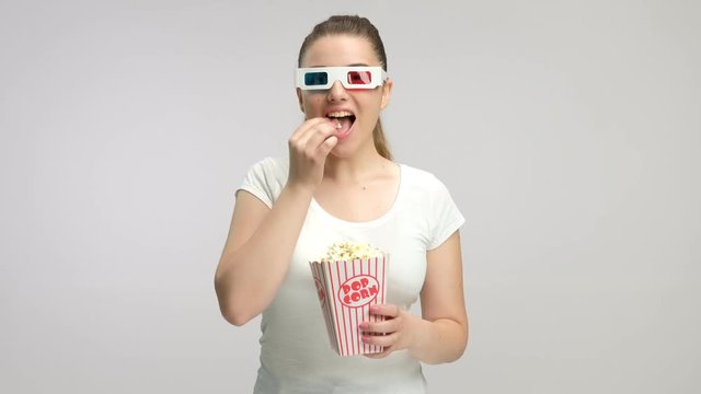 Young girl with 3D glasses eating popcorn and laughing