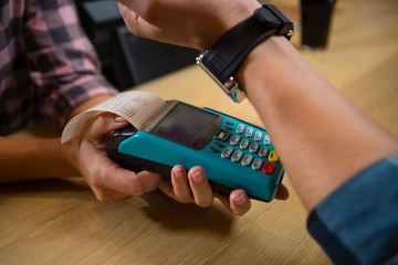 Cropped hand of customer making payment at bar