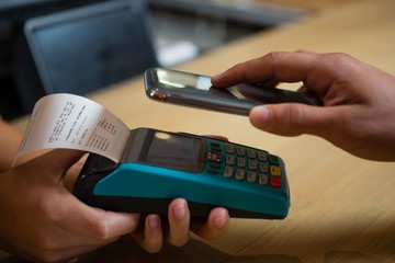 Cropped hand of customer making payment at bar