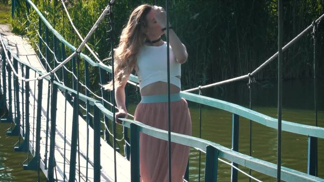 Young beautiful woman waling on the suspension bridge