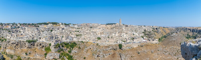 Fototapeta na wymiar panoramic view of typical stones (Sassi di Matera) and church of Matera UNESCO European Capital of Culture 2019 under blue sky. Basilicata