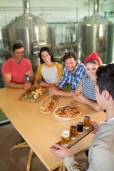 Obraz premium High angle view of bartender serving beer glass to friends
