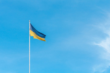 The national yellow-blue flag of Ukraine in the wind in the background a clear blue sky. There is room for text in the photo.
