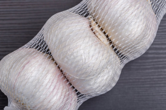 Close up white garlic bulbs in net packaging, general and useful seasoning for tasty foods.