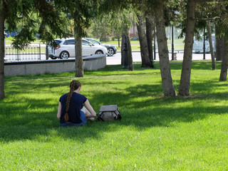 The girl is sitting on the grass in the park