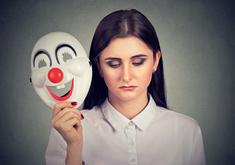sad woman taking off clown mask expressing happiness