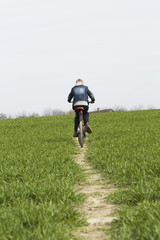 A boy rides on a footpath on a bike