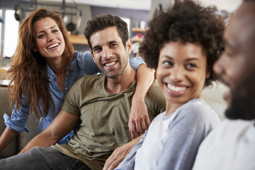 Couple Sitting On Sofa With Friends At Home Talking