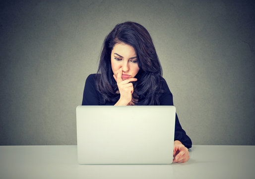Pensive woman working on laptop computer