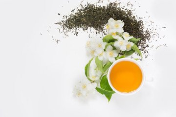 Jasmine dry green tea leaves with fresh jasmine flowers and cup of tea on white background.