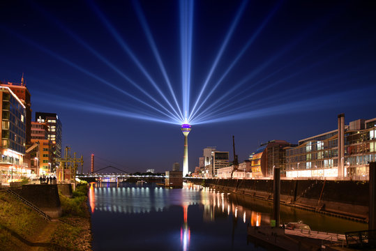 panoramic skyline view Duesseldorf, Germany - media habor district during sunset with iluminated rhine tower and huge laser rays into the sky