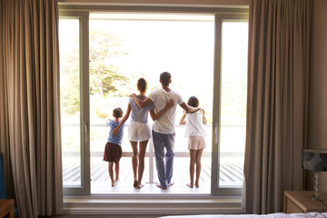 Rear View Of Family On Balcony Looking Out On New Day - Powered by Adobe