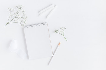 Workspace with notebook, paper blank, gypsophila flowers, pencils. Wedding concept. Flat lay, top view