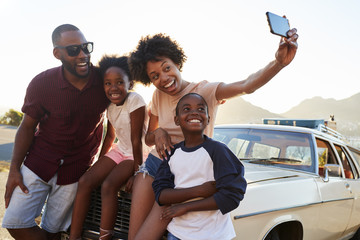 Family Posing For Selfie Next To Car Packed For Road Trip - Powered by Adobe