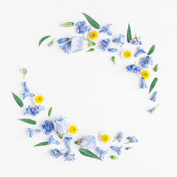 Fototapeta Flowers composition. Wreath made of blue and yellow flowers on white background. Flat lay, top view