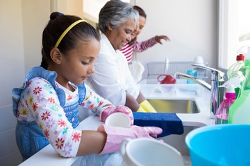 Family washing utensils in kitchen sink