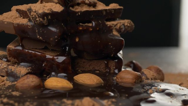 Stack of broken pieces chocolate with nuts, topping and cacao powder