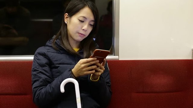 Woman using cellphone inside train compartment