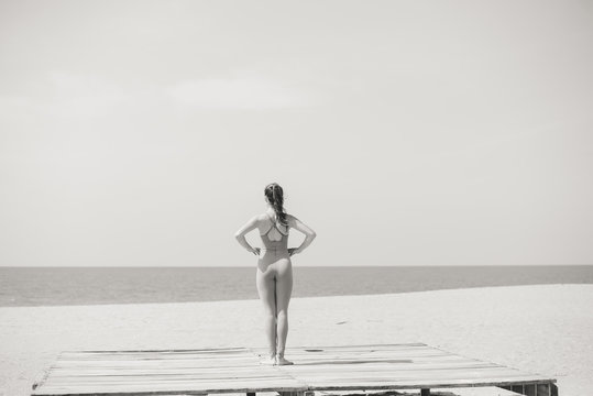 Back view of attractive fit woman sport stretching over the sea outdoor sunny background. Black and white photography