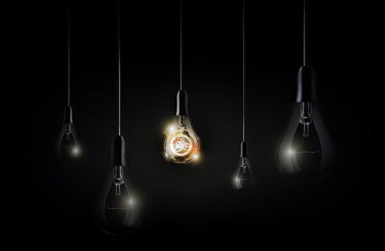Glowing abstract futuristic light bulb is hanging between a lot of turned off light bulbs on dark black background, vector illustration