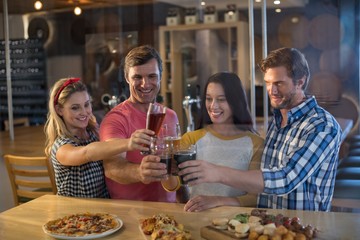 Happy friends toasting beer while standing in bar