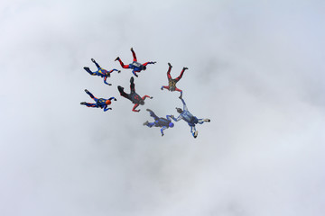 A group of skydivers is flying above the white clouds