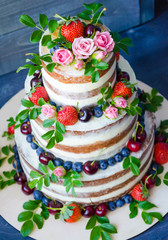Naked wedding cake decorated with berries and flowers