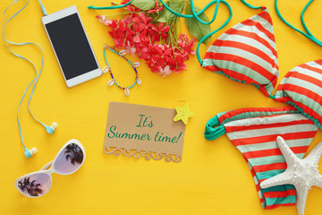 Fototapeta premium Top view of fashion female swimsuit bikini on yellow wooden background