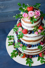 Naked wedding cake decorated with berries and flowers