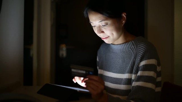 Woman using tablet computer for online shopping at night