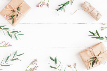 Flowers composition. Gifts, pink flowers and eucalyptus branches on wooden white background. Flat lay, top view