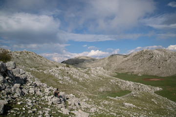 Fototapeta na wymiar Escursionista seduto sulla montagna, Monte Cervati, Parco Nazionale del Cilento e Vallo di Diano, primavera