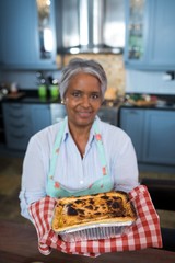 Portrait of senior woman showing baked food