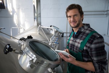 Smiling worker using digital tablet at factory